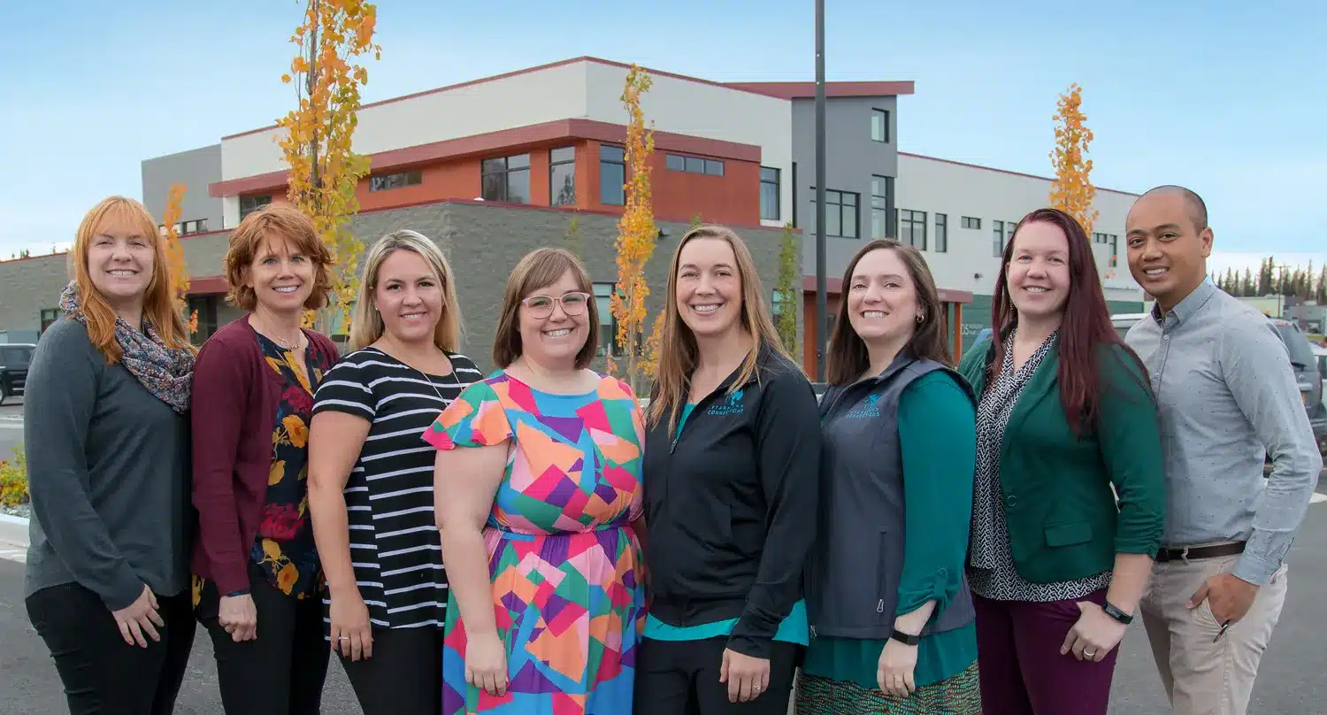 Corporate team photo of staff outside a modern office building in Alaska