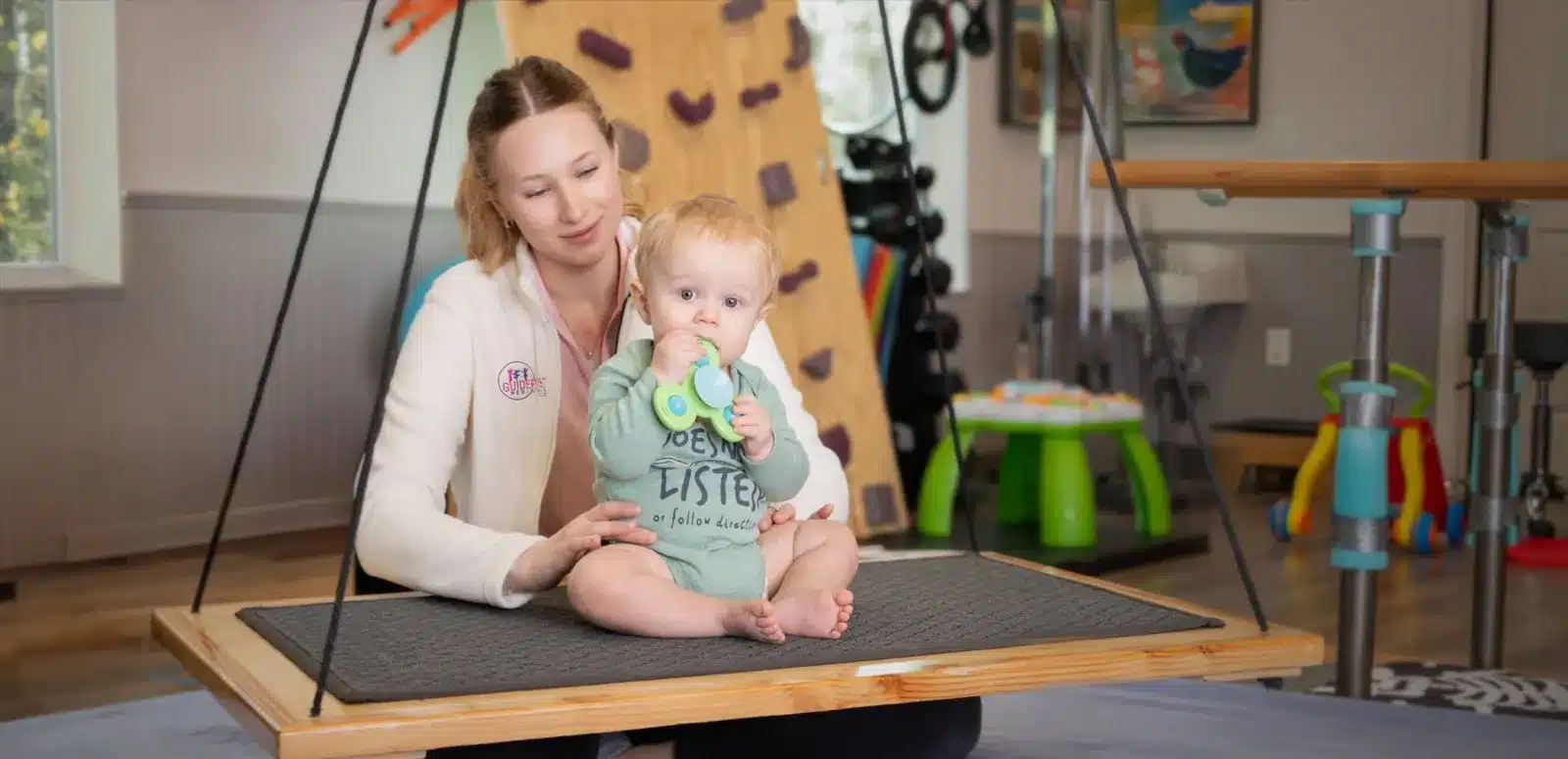Therapist and infant on a therapy swing in a pediatric clinic, healthcare content photography