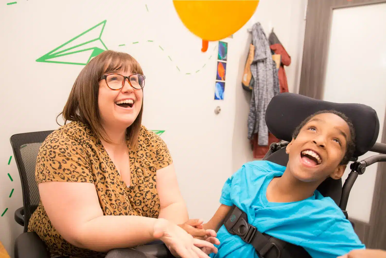 Laughing therapist with a young patient in a pediatric therapy room